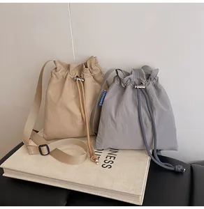 Détail du sac seau en nylon imperméable avec cordon de serrage et boucle sur un livre