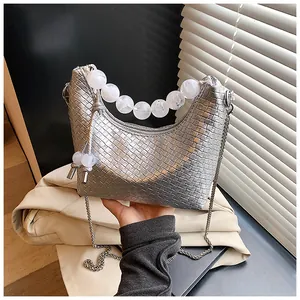 Détail du sac hobo tressé argenté avec poignée en perles et bandoulière en chaîne