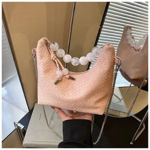 Détail du sac à main rose avec motif crocodile et anse décorative en perles nacrées