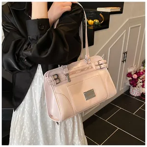 Detail of pink faux leather bag with metal logo plate and decorative buckle straps