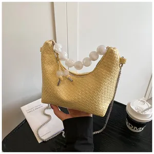 Détail du sac tressé jaune avec poignée en perles et bandoulière en chaîne argentée