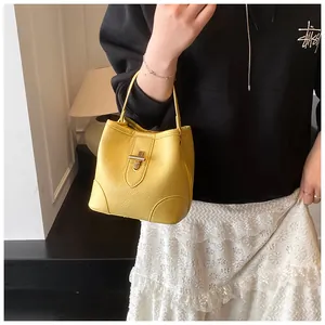 Detailed macro view of yellow bucket bag with lychee grain leather and golden metal twist lock