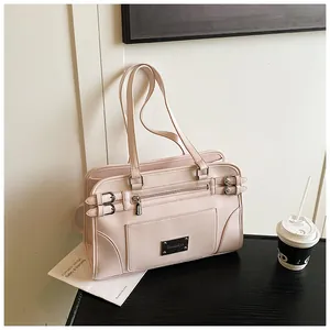 Detail of light pink faux leather handbag featuring metal buckles and zippered pocket