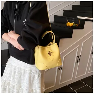 Close-up of bright yellow bucket bag in pebble leather with golden metal twist lock detail