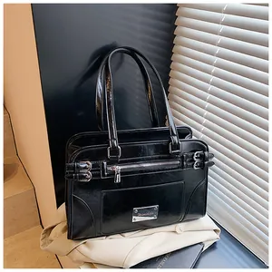 Detail of black glossy faux leather handbag featuring silver hardware and side buckle straps