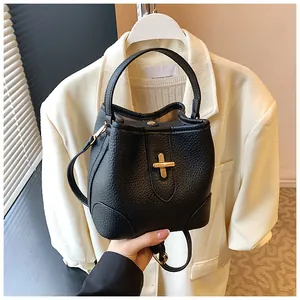 Close-up of black textured leather bucket bag featuring a golden turn-lock closure
