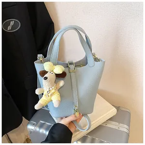 Detail of light blue lychee pattern bucket bag with cute puppy pendant and metal padlock