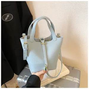 Detail of light blue bucket bag with pebble leather texture and gold hardware details