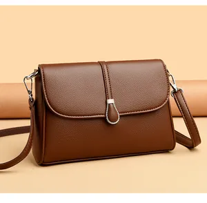 Detail view of brown pebbled leather texture and silver teardrop buckle on a handbag