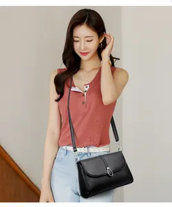 Asian model wearing a black litchi pattern leather crossbody bag with silver teardrop buckle