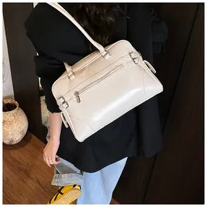 Detail view of cream leather tote bag featuring a vintage design with polished metal hardware