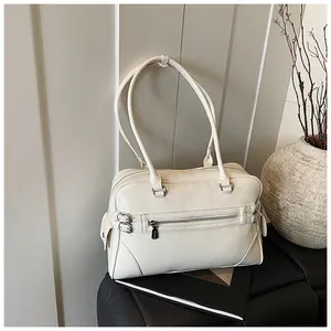 Close-up of a cream PU leather tote bag with decorative zippers and side buckle details