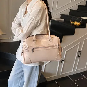 Light pink glossy tote bag with buckle details and zippers shown on a shoulder model