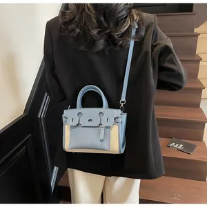 Detail view of blue litchi leather and beige canvas contrast bag on stairs