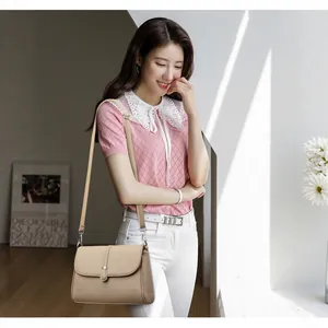 Beige lychee leather crossbody bag with silver U-shaped buckle and adjustable strap