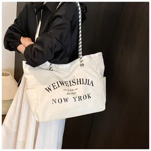Détail du sac cabas en toile montrant la poche latérale et la bandoulière en corde tressée
