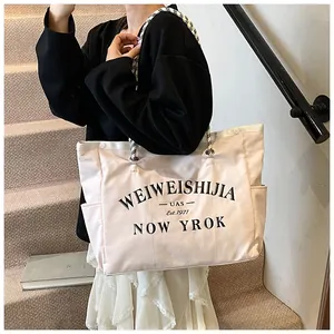 Détail du sac cabas en toile rose avec lettres noires et anses en corde tressée à l'épaule