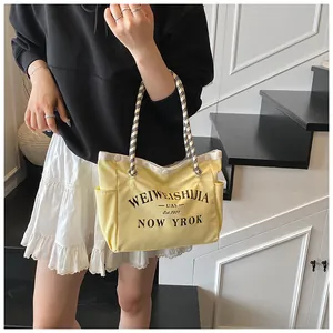 Détail du sac fourre-tout en toile jaune avec imprimé et poignées en damier tressé