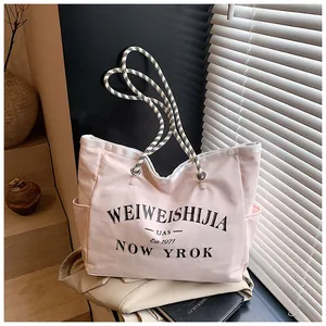 Détail du sac cabas en toile rose avec anses en corde tressée et lettrage noir