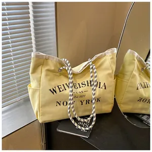 Détail d'un grand sac cabas en toile avec poignées tressées et imprimé de lettres