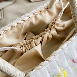 Detailoverzicht van geweven strooien tas met beige trekkoordvoering en kanten versiering