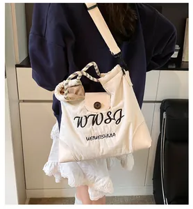 Detail of cream canvas tote bag featuring black embroidery and woven rope handle