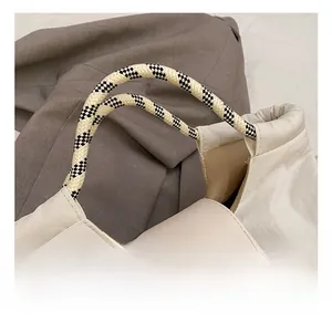 Detail of checkered woven handle and round button closure on casual beige tote bag