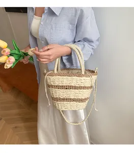 Détail du sac seau en paille tressée avec motif à rayures et fermeture à cordon sécurisée