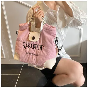 Detail of pink quilted tote bag showing embroidered text and checkered woven handles