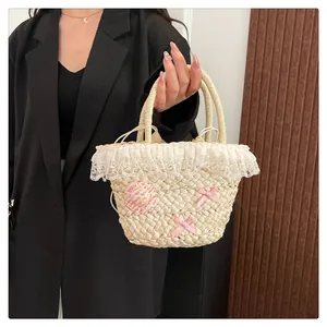 Detail van rieten handtas met kantafwerking, roze strikken en binnenvoering met koord