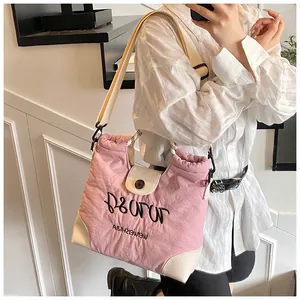 Detail of pink nylon tote bag featuring adjustable drawstring and black letter embroidery