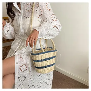 Vue détaillée d'un sac seau tressé à rayures bleues porté sur une robe blanche