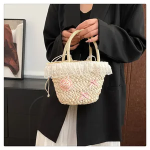 Detail van strooien tas met witte kanten rand en roze zijden strik als decoratief accent