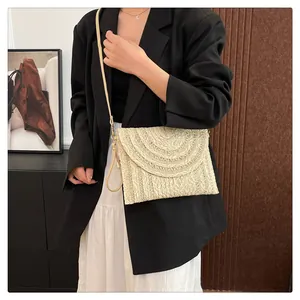 Detail of beige straw envelope bag with woven texture, flap design, and slim shoulder strap