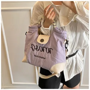 Detail of lavender and cream crossbody bag with soft nylon texture and letter embroidery