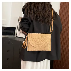 Detail of bohemian woven envelope bag with shoulder strap and wristlet on a model