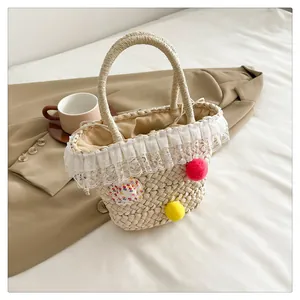 Platte weergave van strooien tas met kant, kleurrijke pompons en regenboog accent detail