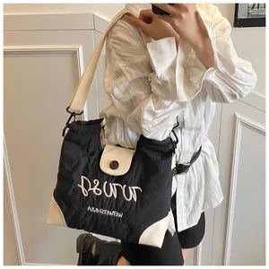 Detail of black canvas tote bag with white embroidery and adjustable wide shoulder strap