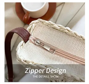 Close-up van het ritsontwerp van deze geweven strooien crossbody zadeltas