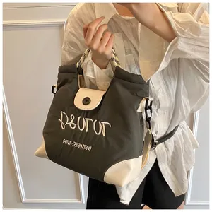 Detail of dark olive canvas tote with white embroidery and checkered handles