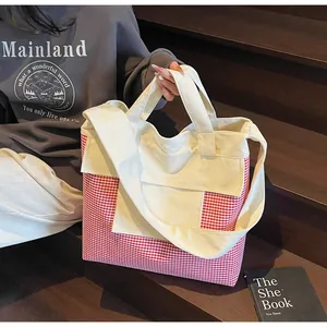 Detail of red gingham canvas tote bag with front pocket held by model in casual setting