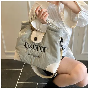 Detail of grey-green tote bag featuring white leather trim and black embroidered lettering