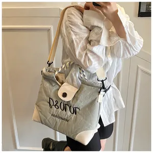 Close-up of grey nylon tote bag with white reinforced corners and embroidered lettering