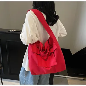 Vista dettagliata di una grande borsa tote in tela rossa con design a fiocco su modella