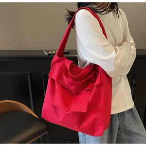 Detail of red canvas tote bag with ruffles and wide shoulder strap shown on a model