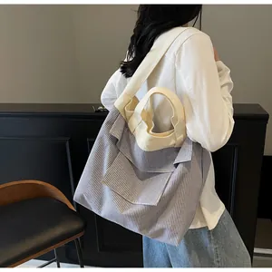 Detailed side view of striped canvas tote bag worn by a model in a modern office setting