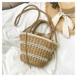Vue de dessus d'un sac seau tressé avec cordons et chapeau de paille sur lin blanc