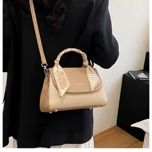 Detail of khaki woven crossbody bag with fashion lettering and silk scarf wrapped handle