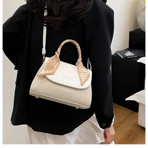 Detail of cream crossbody bag with textured weaving and decorative silk scarf on handle