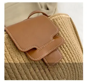 Detail der Strohtasche mit braunem Lederverschluss und kontrastierenden Nähten